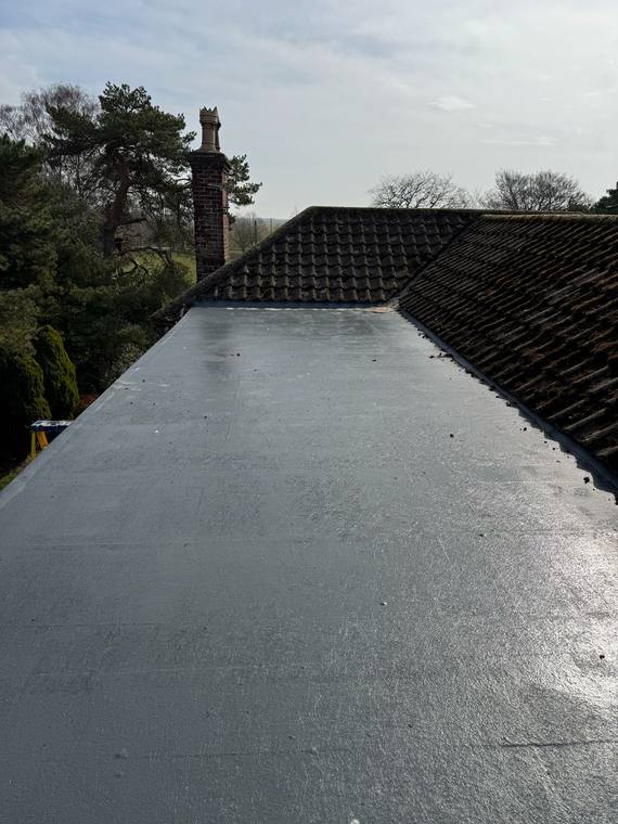 GRP flat roof meeting a tiled pitched roof, with a chimney in the background