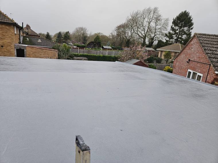 Large light grey GRP flat roof with gardens and trees behind